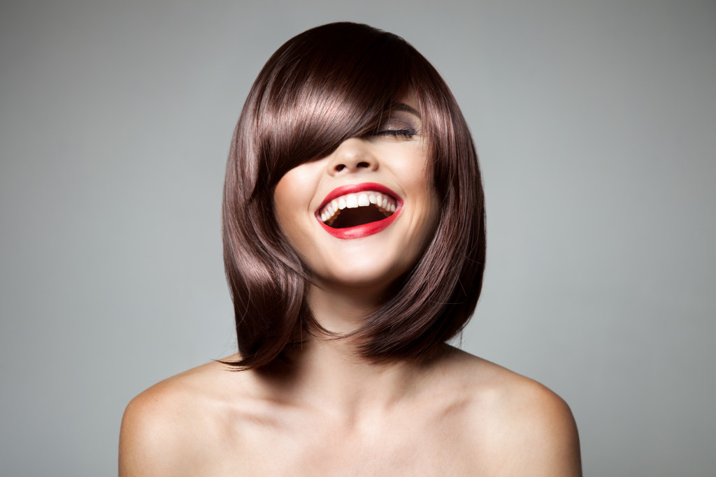 A smiling woman with a sleek, brown bob and red lipstick